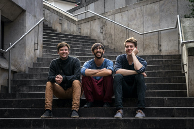 Die Gründungsmitglieder von Carlo auf einer Treppe sitzend: Chris Roemer, Julius Schmitt und Tobias Wolf
